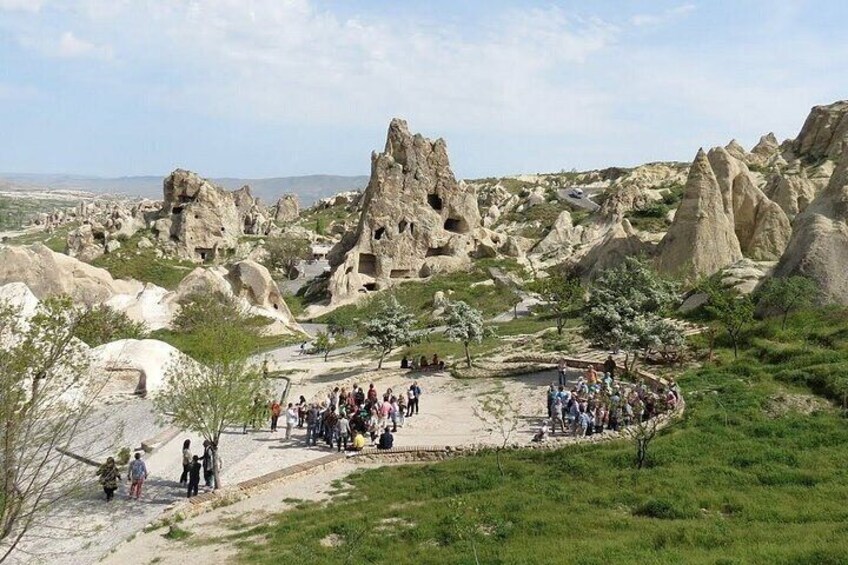 Un paysage rocheux parsemé de formations géologiques uniques, un groupe de personnes rassemblées au premier plan et un ciel dégagé. 1