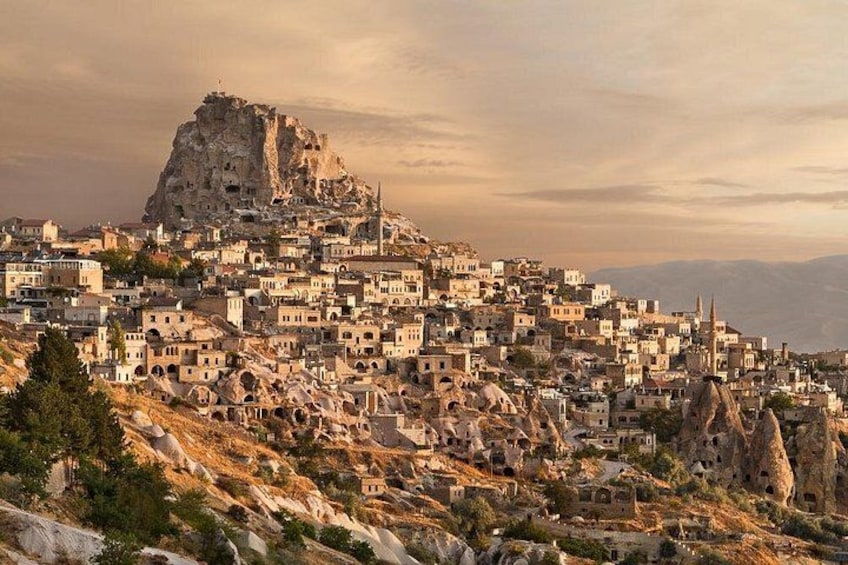 A town with a prominent rocky hill, numerous buildings, and a mosque. 1