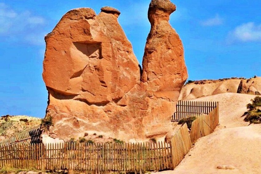 A large rock formation with a wooden fence in the foreground. 3