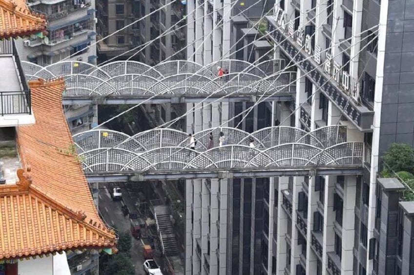Een voetgangersbrug met een traditioneel dak en moderne gebouwen. 4