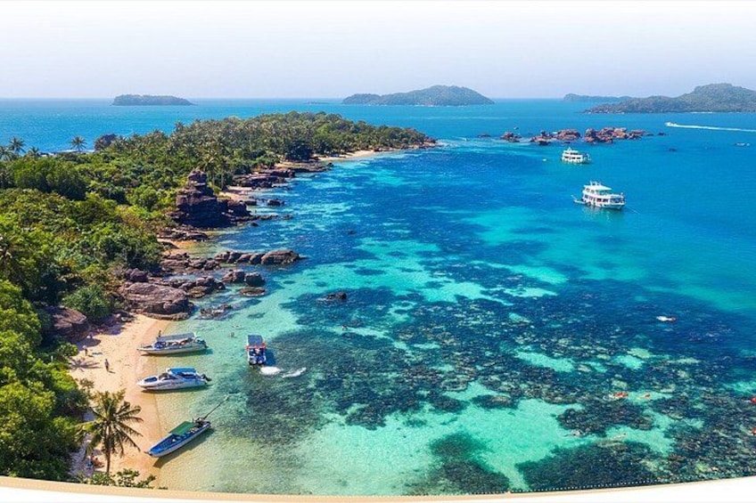 A coastal area with clear turquoise waters, boats, and lush greenery. 3