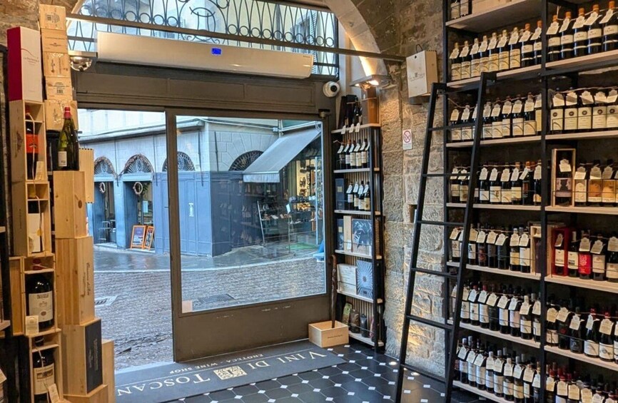 A wine shop with shelves of bottles and a view of the street outside. 5