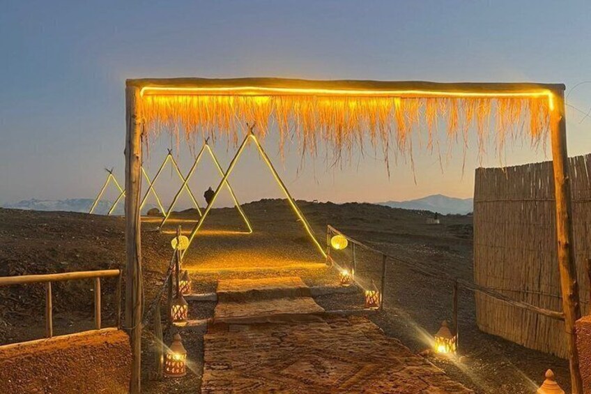 Un arco in legno con luci e lanterne appese, che conduce attraverso un paesaggio arido. 1
