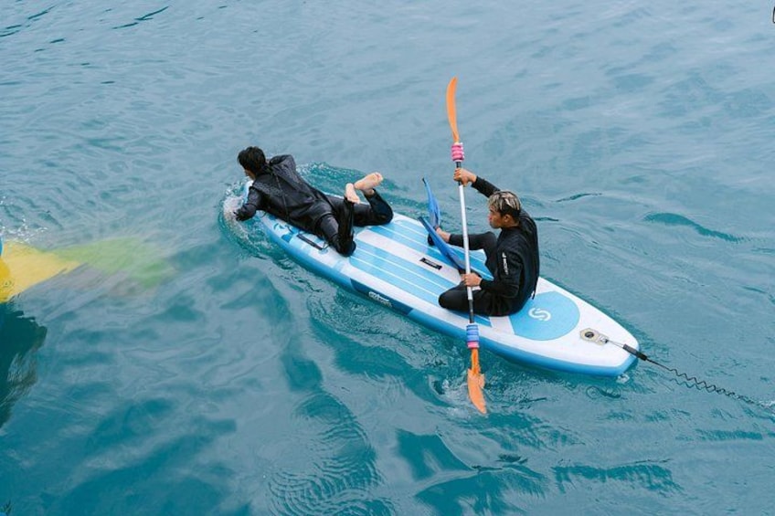 Two people on a blue and white paddleboard in the water. 3