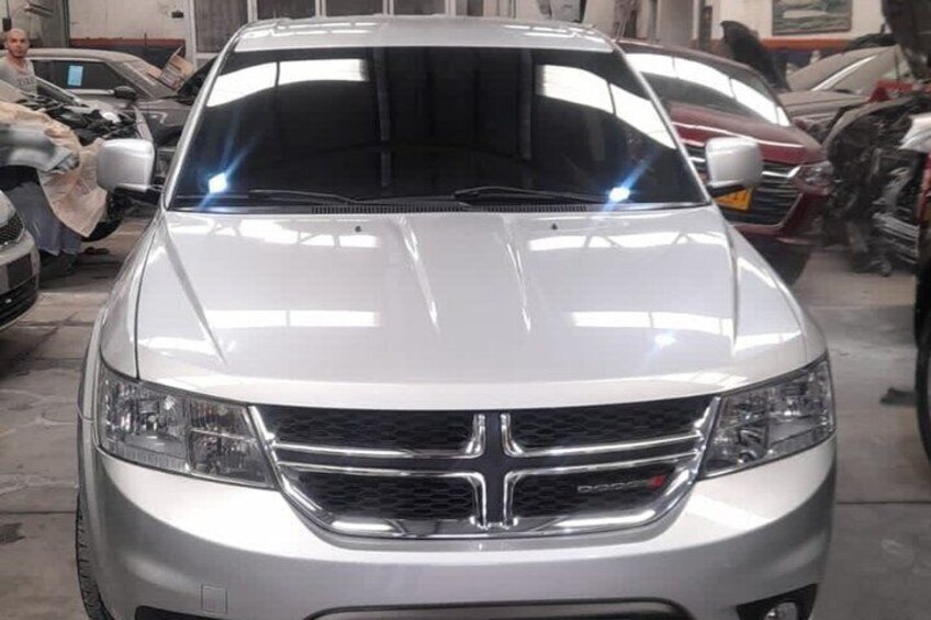 Un'auto argentata con una mascherina anteriore importante e fari, parcheggiata in un garage con altri veicoli. 5
