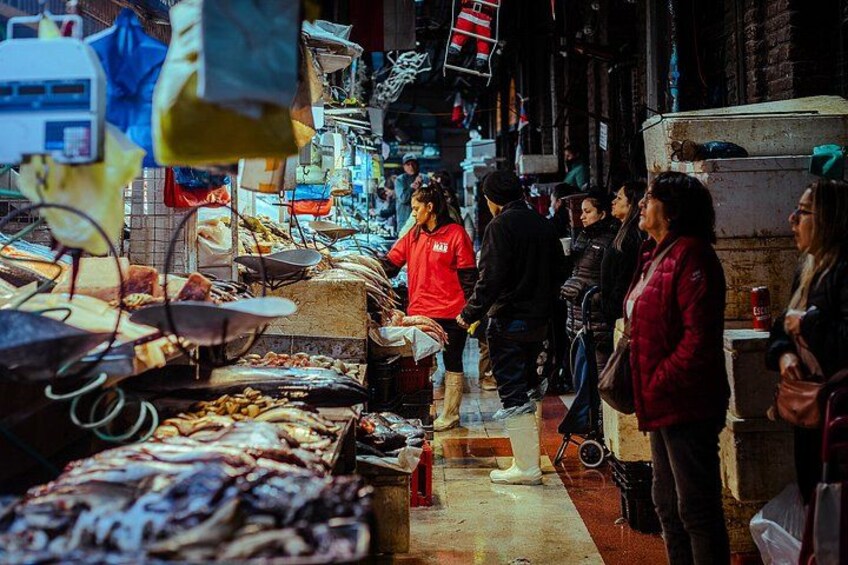 A market with people shopping and a vendor in a red shirt. 5