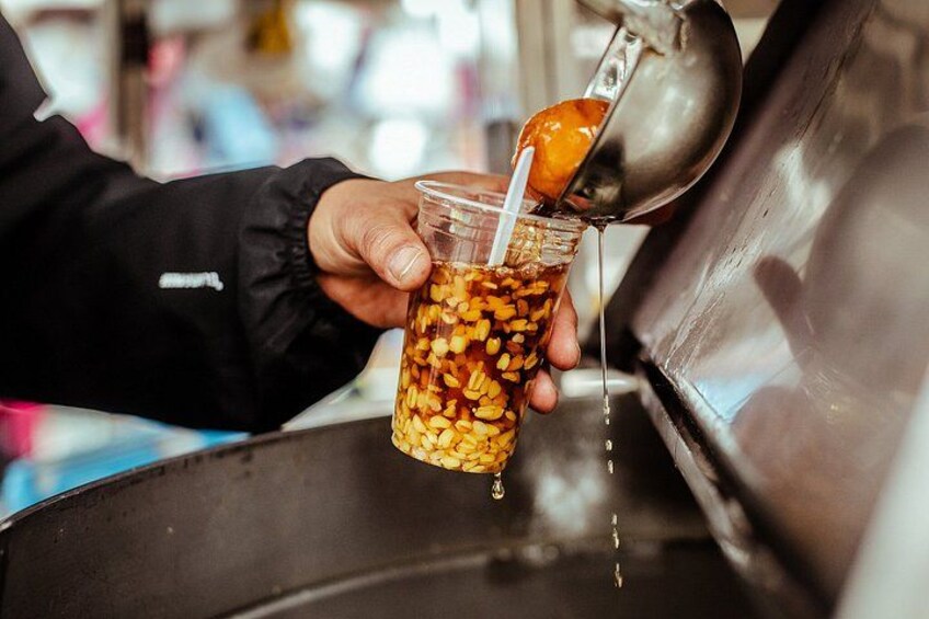 A person pouring a drink from a container filled with nuts into a glass. 2