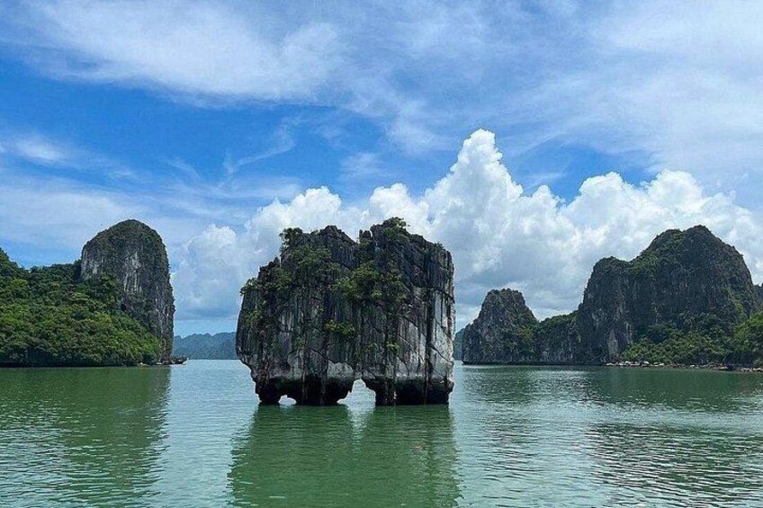A large rock formation surrounded by water and greenery. 2