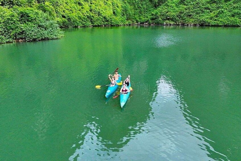 A group of people kayaking on a green river surrounded by dense greenery. 3