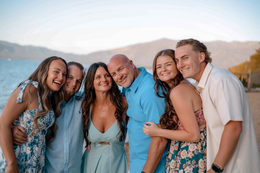 A group of people standing by a body of water with mountains in the background. 5