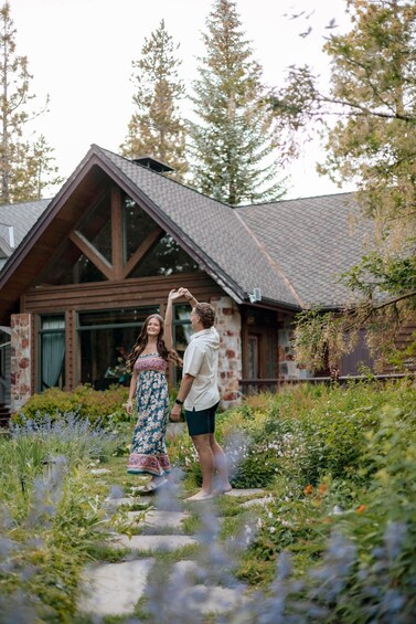 A couple walking on a stone path in a garden with a wooden house in the background. 4