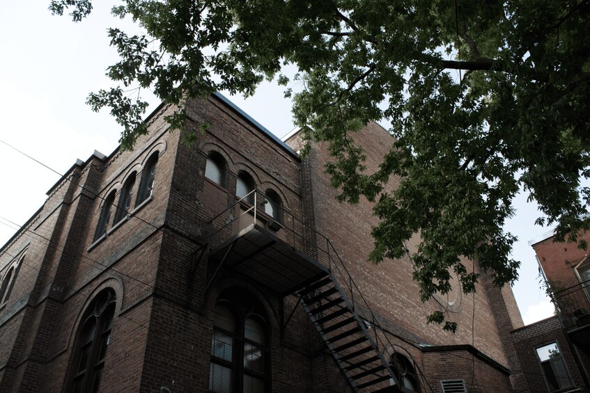 A brick building with arched windows and a fire escape. 2