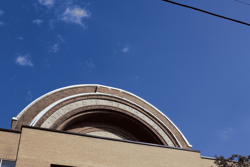 A building with a curved brick archway and a clear blue sky. 4