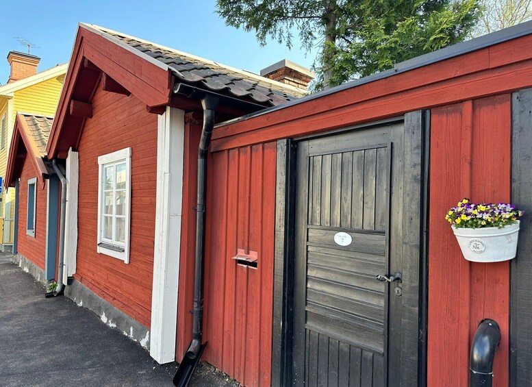 A red wooden building with a dark door and a flower pot on the right side. 2