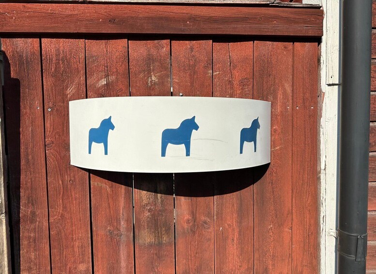 A wooden fence with a white sign featuring horse silhouettes. 3