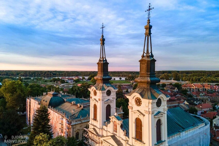 A church with two spires and a dome, surrounded by a town. 1