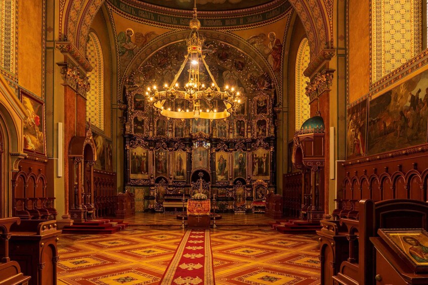An ornate church interior with a large chandelier, detailed woodwork, and religious paintings. 4