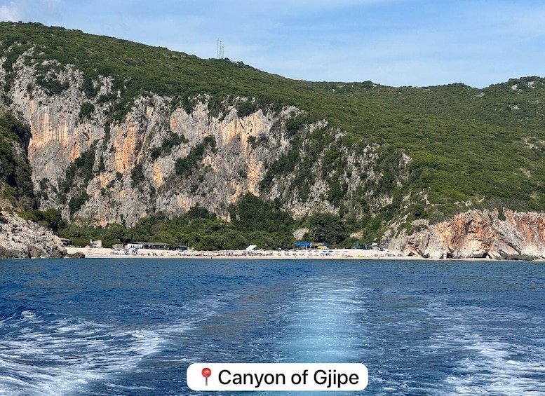 A coastal landscape with a canyon, beach, and clear blue sea. 1