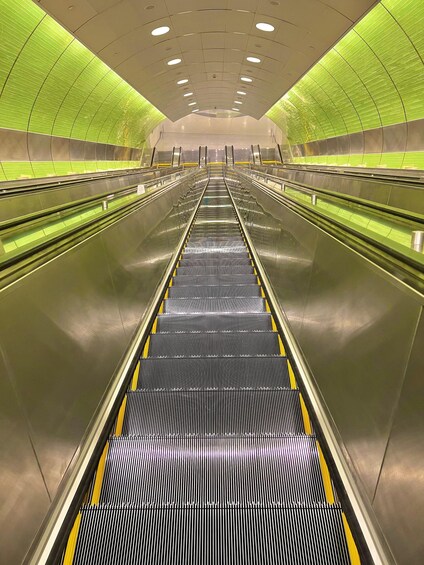 An escalator in a modern building with green walls and a reflective floor. 5