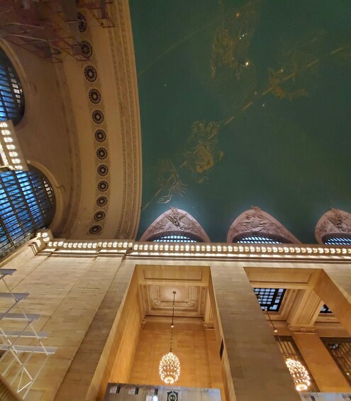 An interior with a high ceiling, ornate ceiling decorations, and a large skylight. 4