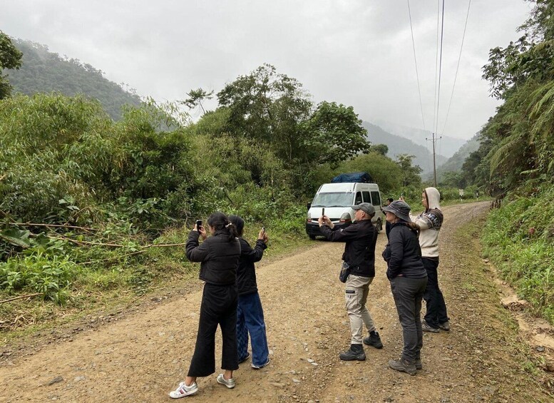 A group of people taking photos on a dirt road with a white van parked nearby. 2