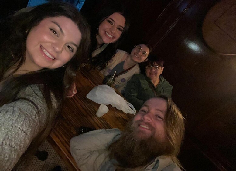 A group of people sitting on a wooden floor, possibly in a restaurant or bar. 5