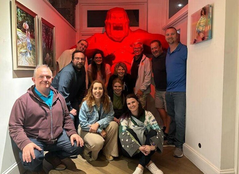 A group of people posing in front of a large red sculpture in an indoor setting. 4
