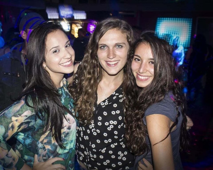 Three people in a dimly lit indoor setting with a digital screen in the background. 5