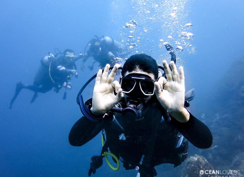 A diver underwater with bubbles, surrounded by other divers. 3