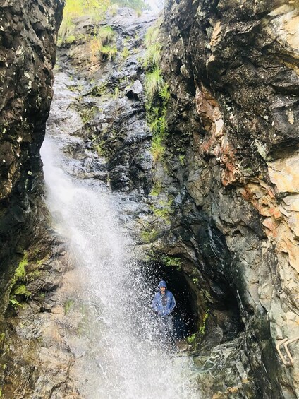 A person standing in a rocky gorge with a waterfall. 2