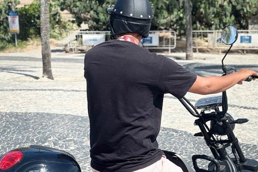Eine Person fährt Motorrad auf einer asphaltierten Straße, im Hintergrund Bäume und ein Zaun. 5