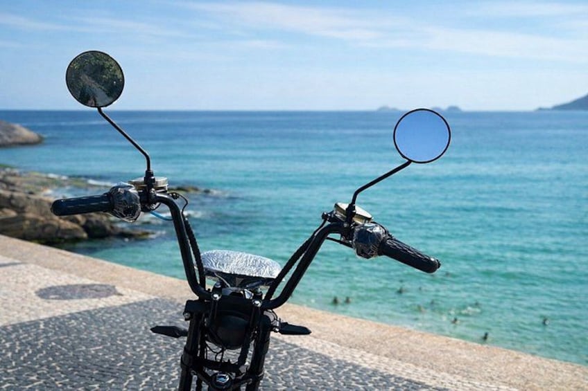 Ein Motorrad steht auf einer befestigten Fläche mit Blick auf das Meer und die felsige K üste. 1