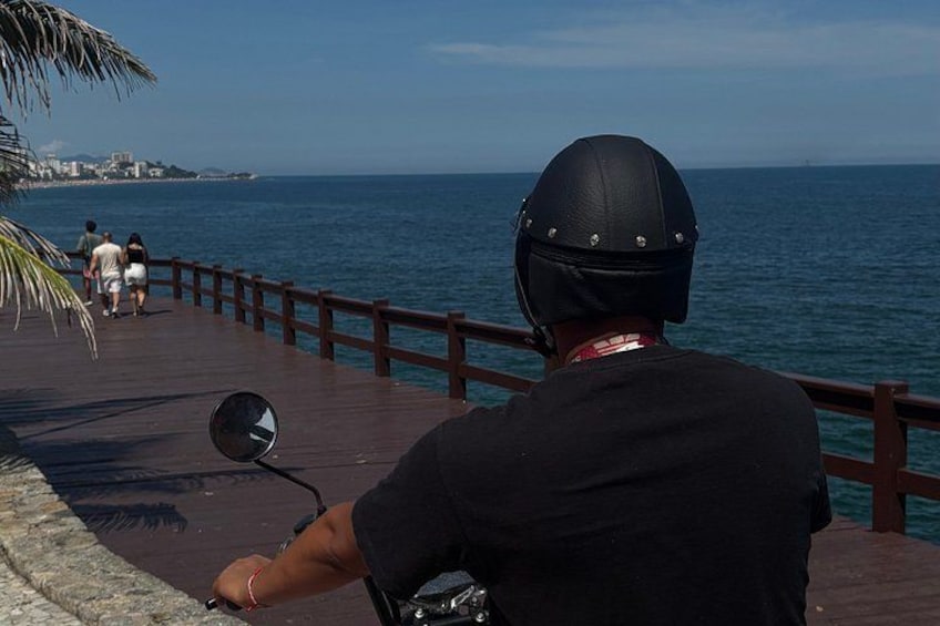 Eine Person fährt auf einem Motorrad auf einem hölzernen Promenadendeck am Meer. 2