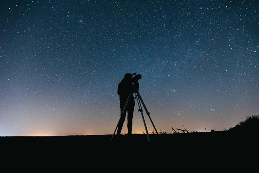 A person with a telescope under a starry night sky. 3