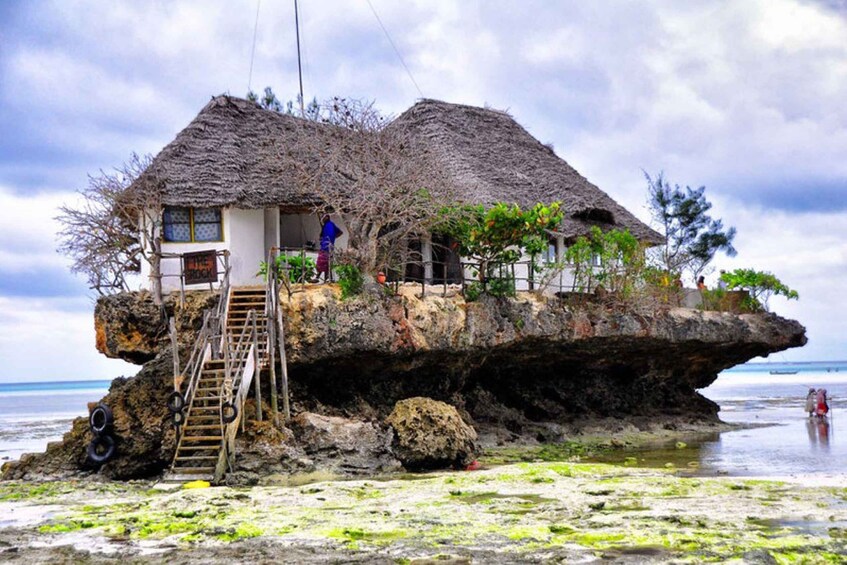 A house built on a rock formation with a staircase leading up to it. 2