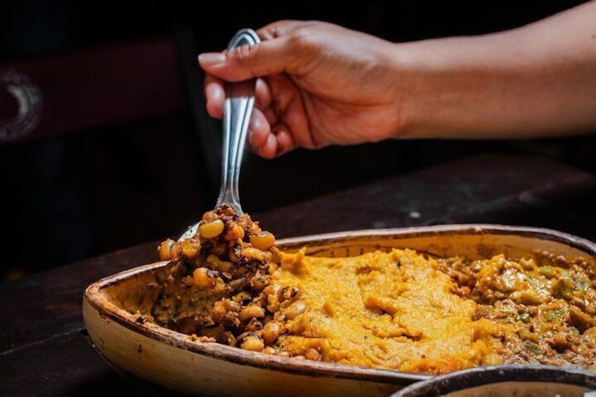 A hand scooping food from a pan. 1