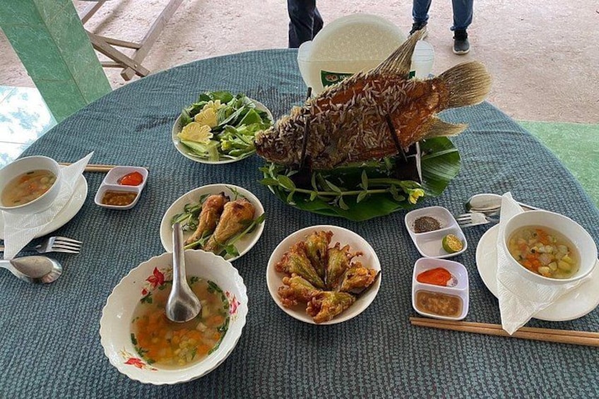 A table with a variety of dishes including a whole fried fish, bowls of soup, and plates of vegetables. 4