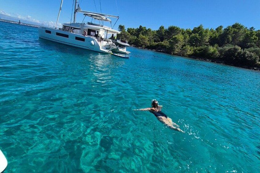 A person swimming in clear blue water with a boat in the background. 4