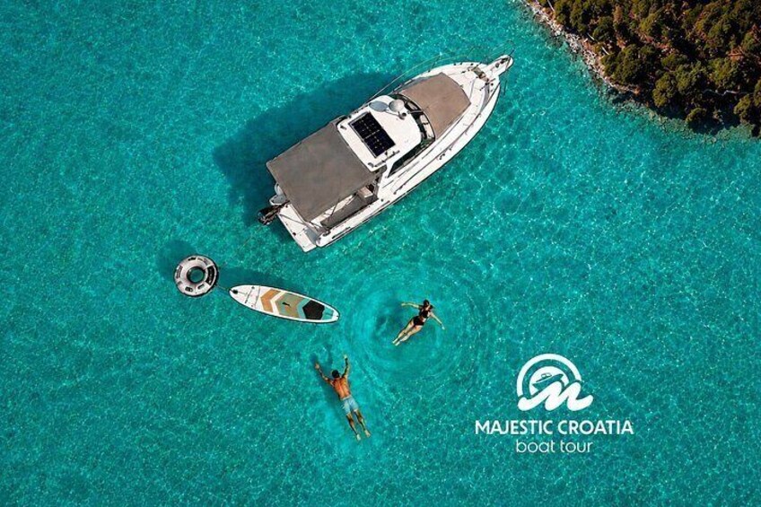 A boat tour in Majestic Croatia with a yacht, a smaller boat, and two people swimming. 1