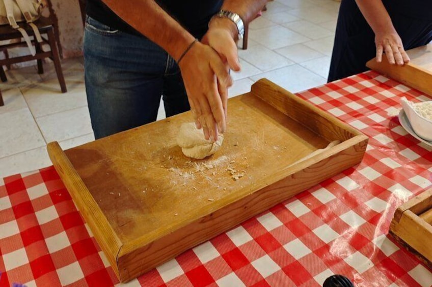Una persona amasa masa sobre una superficie de madera con mantel a cuadros. 5