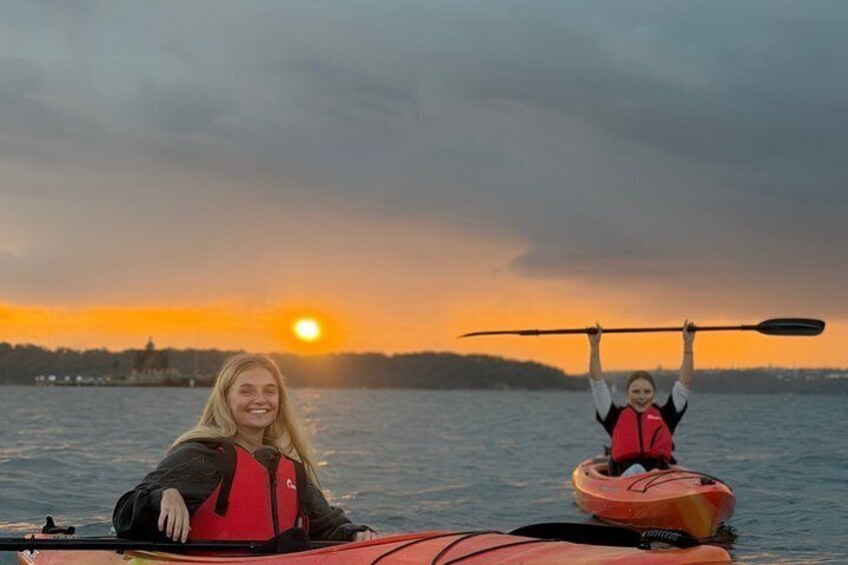 Due persone che fanno kayak su un corpo d'acqua con un tramonto sullo sfondo. 4