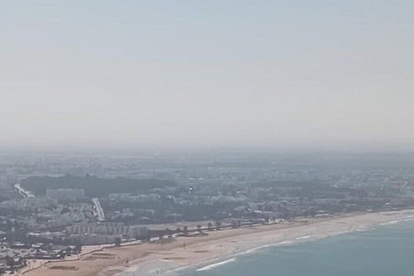 A coastal cityscape with a beach, buildings, and a clear sky. 4