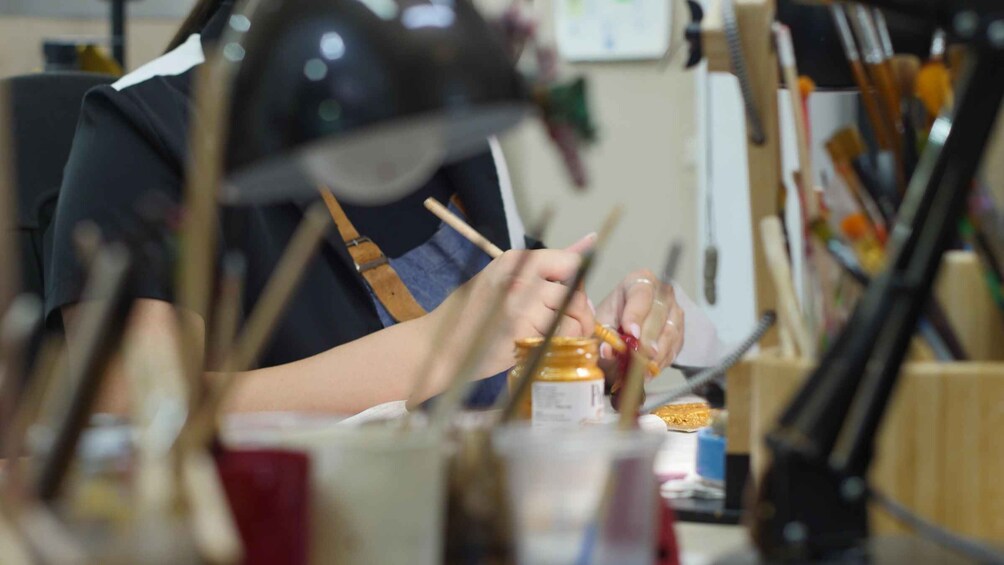 A person painting with a brush, surrounded by art supplies. 3