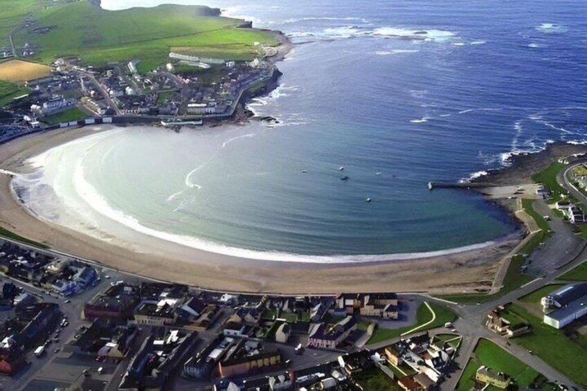 A coastal town with a curved beach, a marina, and residential buildings. 2