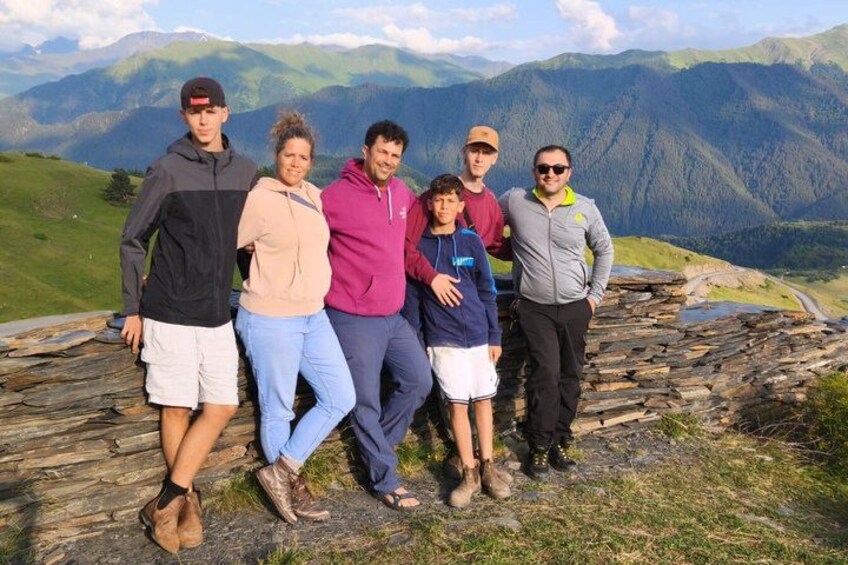 A group of people standing on a stone wall with a mountainous landscape in the background. 3
