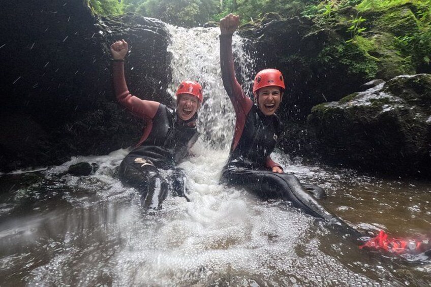 Two people in a river with water flowing over rocks. 2