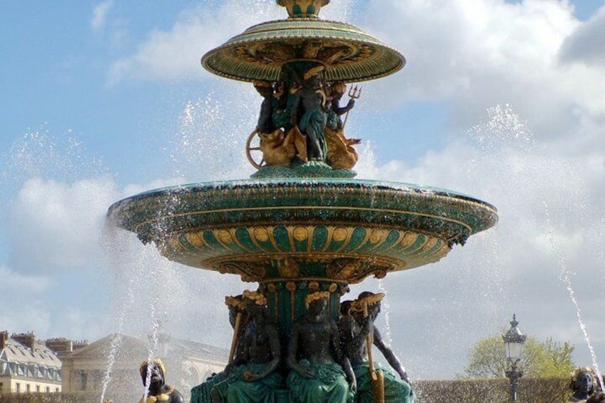 A multi-tiered fountain with statues, surrounded by buildings. 5