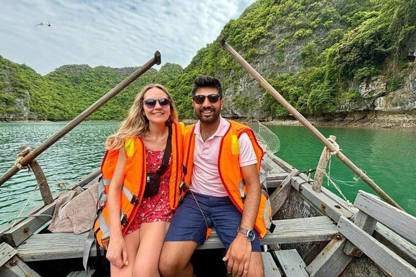 Dos personas en un bote de madera con chalecos salvavidas, rodeadas de un paisaje montañoso y verde. 5