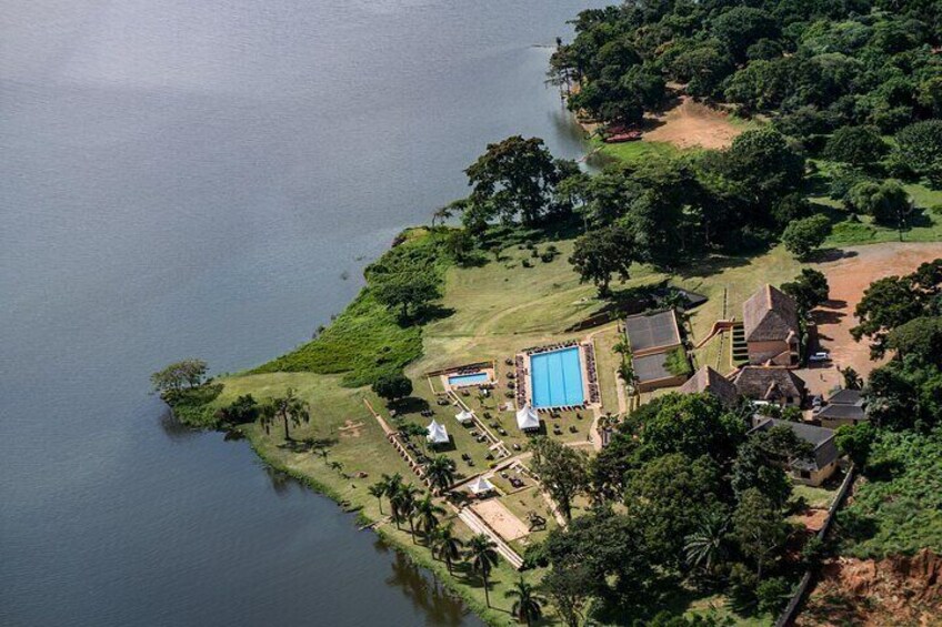 An aerial view of a coastal area with a swimming pool, buildings, and lush greenery. 1