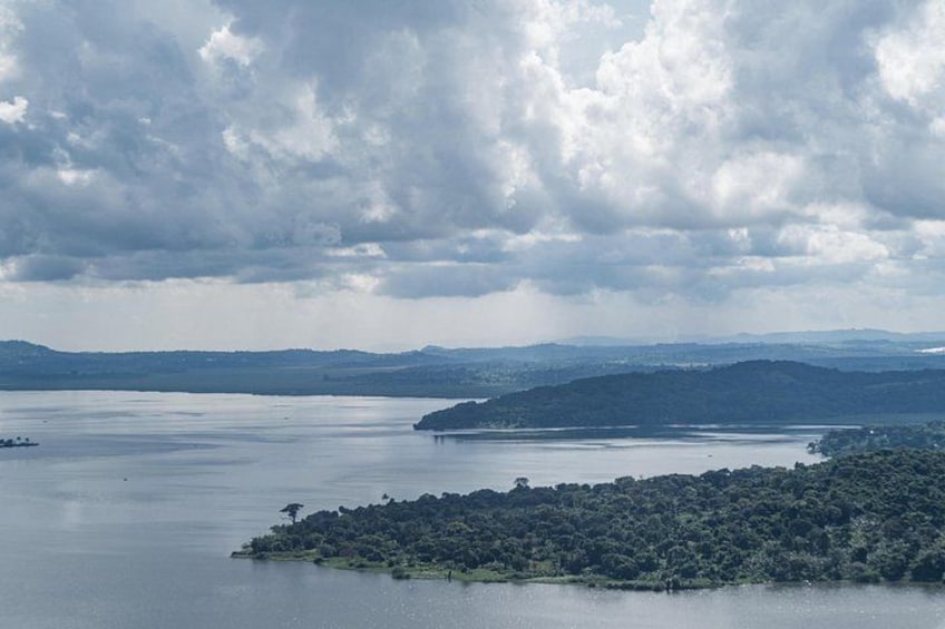 A large body of water with a small island in the foreground and a larger landmass in the background under a cloudy sky. 4